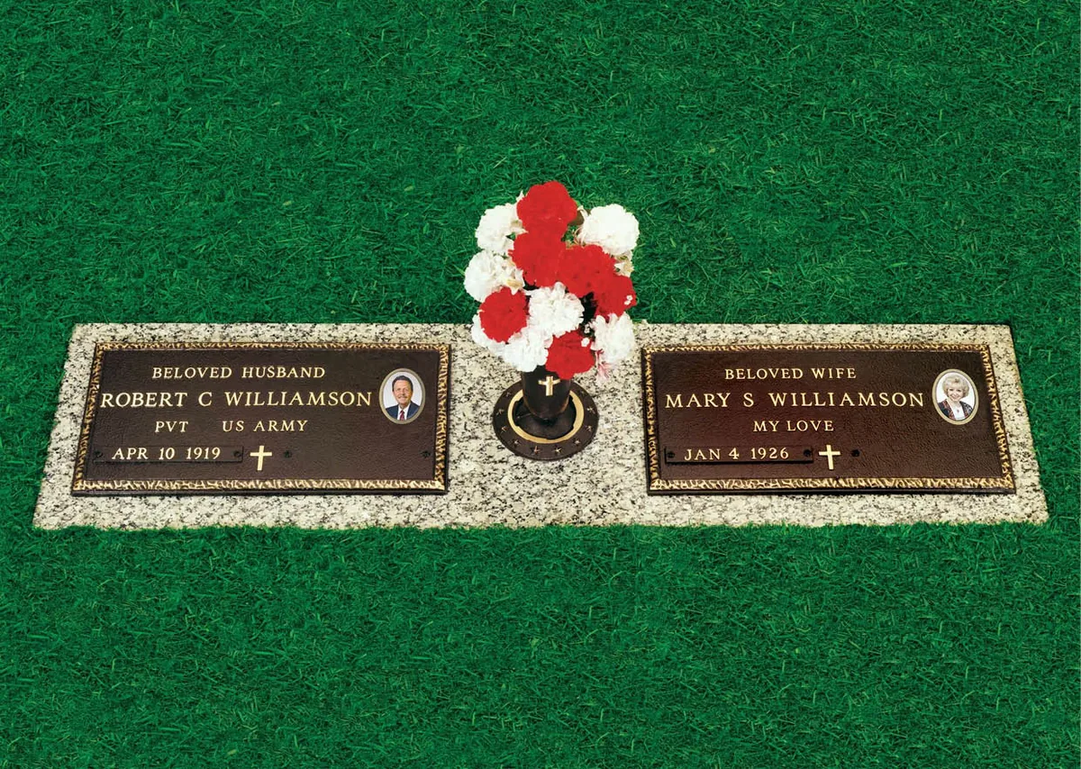 A veteran's government-style bronze marker beside a matching bronze for the spouse, on one granite foundation with a vase between them