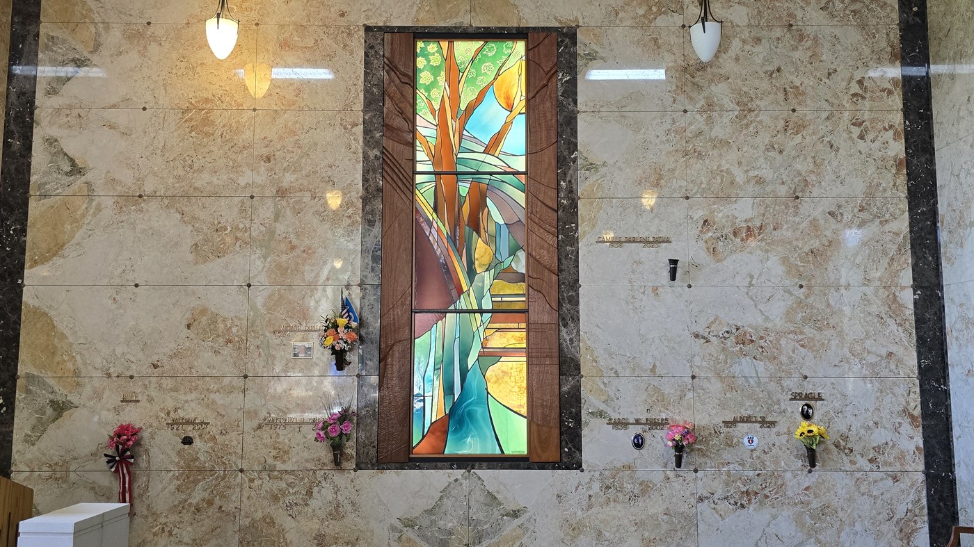 The chapel inside the Chapel of Memories mausoleum: a marble crypt wall around a stained glass window