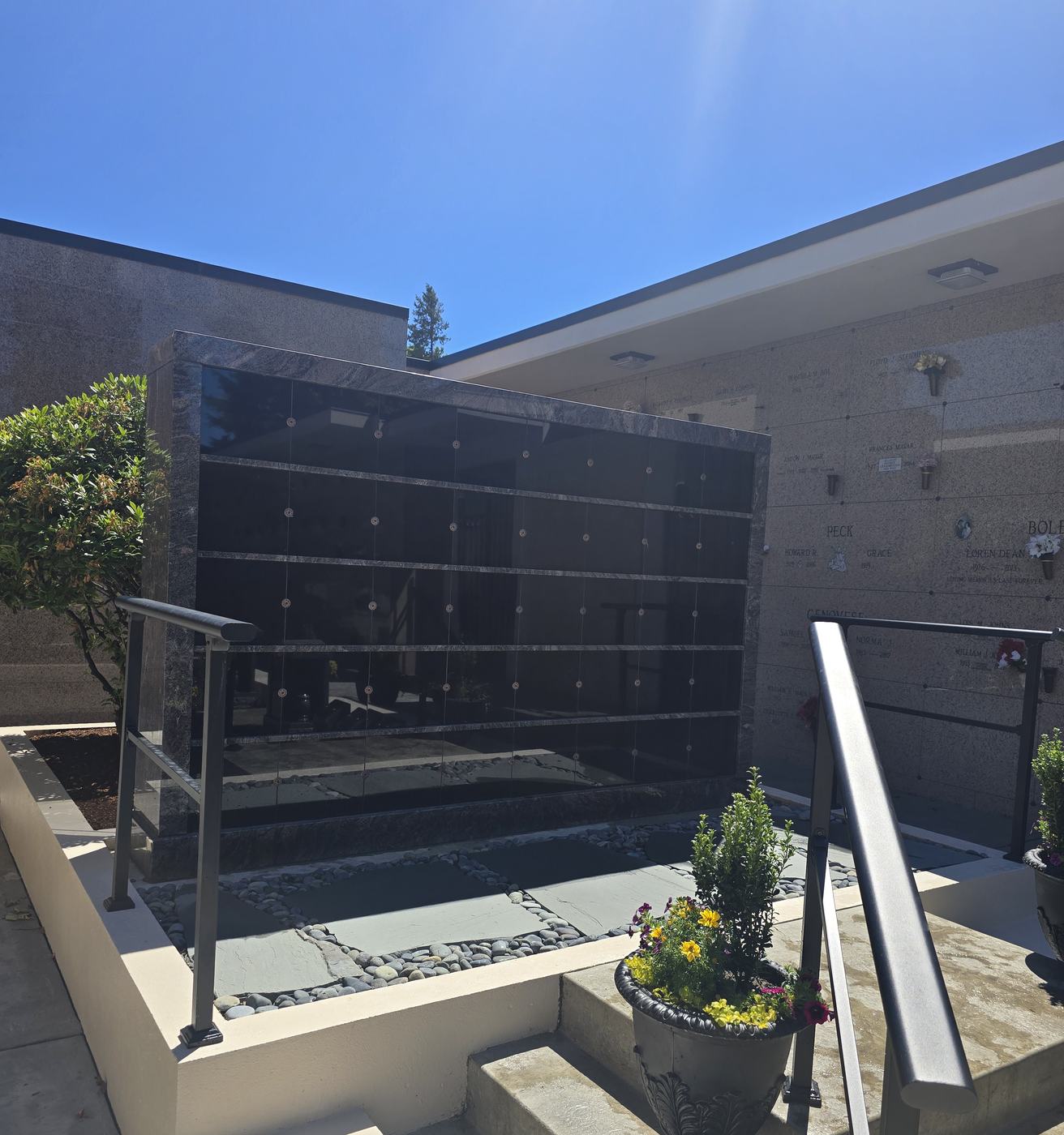 Close view of the Terrace Garden niche bank: rows of blank polished black granite niche fronts each fixed with two bronze rosettes
