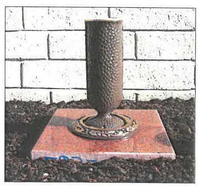 Hammered bronze Doric vase with a floral ring set in a red granite block